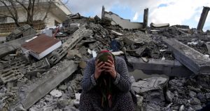 Una mujer sentada sobre los escombros de un edificio que se derrumbó por el sismo del lunes en Nurdagi, sur de Turquía, el martes 7 de febrero de 2023.