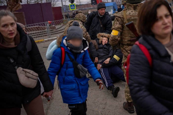 Mientras se oye el ruido cercano de artillería, varias personas huyen de Irpin, a las afueras de Kiev, Ucrania, el lunes 7 de marzo de 2022.