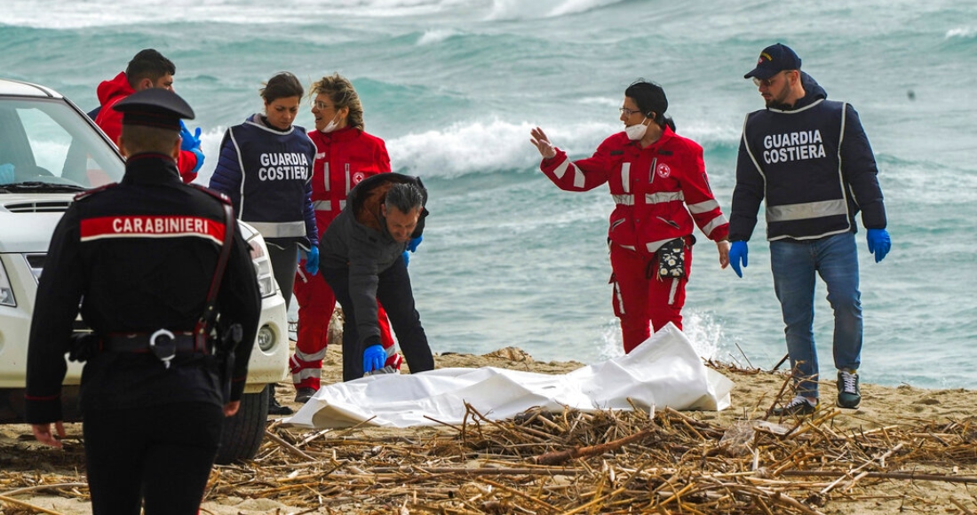 Voluntarios de la Cruz Roja italiana y personal del servicio de guardacostas recuperan un cadáver el domingo 26 de febrero de 2023 luego de que un bote con migrantes se partió en un mar agitado, en una playa cerca de Cutro, en el sur de Italia.