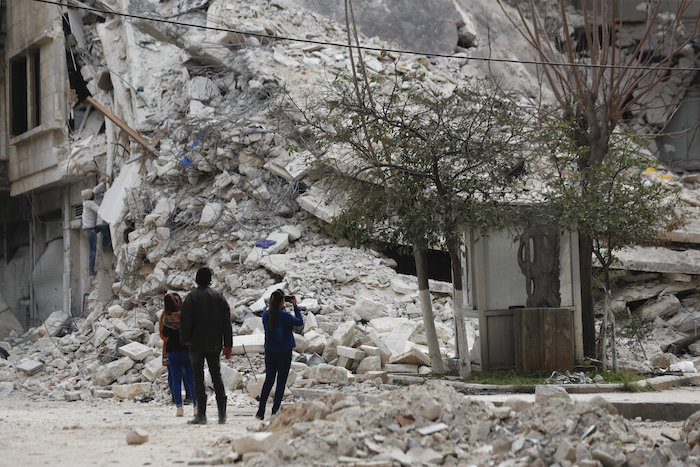 Personas observan un edificio destruido por un terremoto reciente, el lunes 27 de febrero de 2023, en Alepo, Siria.