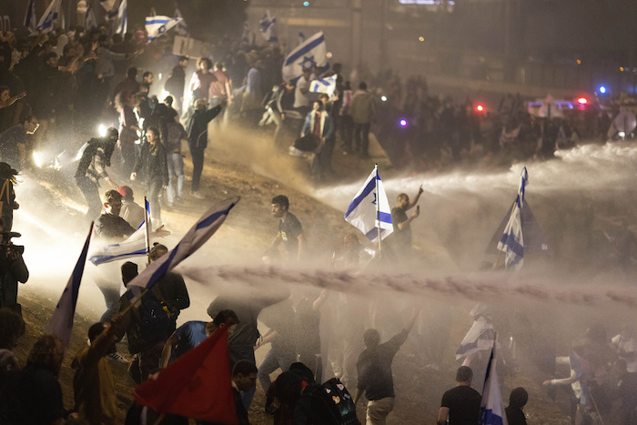 Policías israelíes emplean un cañón de agua para dispersar a los manifestantes que cortan una autopista durante una protesta contra los planes del Primer Ministro, Benjamin Netanyahu, de reformar el sistema judicial del país, en Tel Aviv, Israel, el lunes 27 de marzo de 2023.