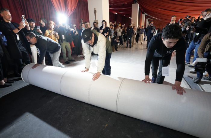 Trabajadores desenrollan la alfombra durante los preparativos para la 95a edición de los Premios de la Academia, el 8 de marzo de 2023, fuera del Teatro Dolby en Los Ángeles.