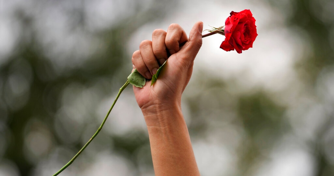 Una manifestante levanta el puño al aire con una rosa roja durante una protesta en Manila, Filipinas, con motivo del Día Internacional de la Mujer, el 8 de marzo de 2023.