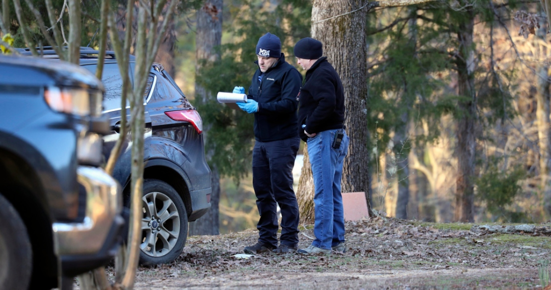 En esta fotografía del viernes 17 de febrero de 2023, agentes policiales examinan el lugar donde ocurrió un tiroteo, en Arkabutla, Mississippi.