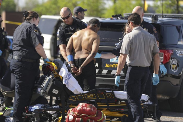 Un hombre esposado recibe atención médica antes de que lo suban a una ambulancia después de un tiroteo fatal en la tienda de autoservicio QuikTrip, en la Calle Pine y Avenida Peoria, en Tulsa, Oklahoma, el martes 18 de abril de 2023.