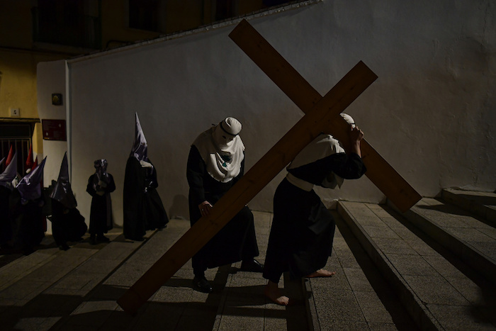 Un penitente con el rostro oculto de la hermandad de "Santa Cracruz" carga una cruz durante una procesión de Semana Santa en Clahorra, norte de España, el miércoles 5 de abril de 2023.