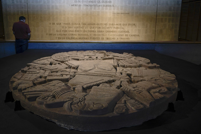 Un visitante lee la información que se muestra en una pared junto a un monolito que representa a la diosa lunar mexica Coyolxauhqui, en el Museo del Templo Mayor, en conmemoración del 45 aniversario del descubrimiento de la piedra circular, en la Ciudad de México, el miércoles 29 de marzo de 2023. El hallazgo marcó un hito para la arqueología mexicana, ya que arrojó luz sobre la civilización mexica antes de la conquista española.