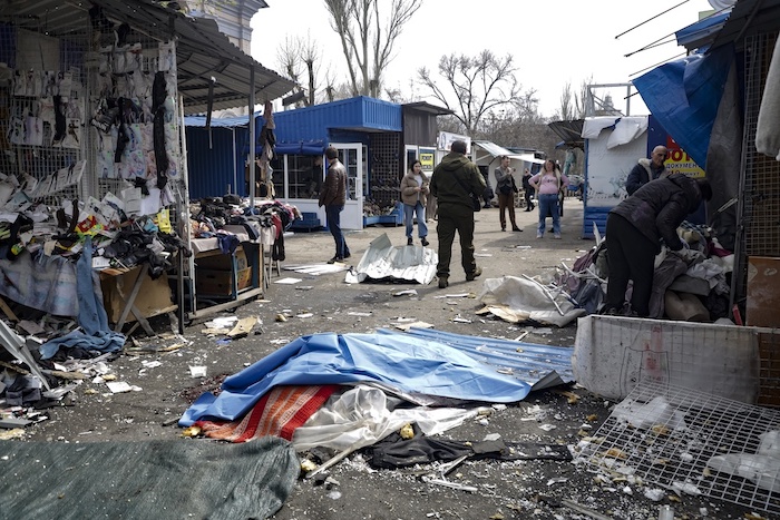 Una persona muerta yace en el piso cubierta con plástico en un mercado callejero tras un ataque de artillería que según autoridades rusas fue realizado por las fuerzas ucranianas, en la zona de Donetsk controlada por los rusos en el este de Ucrania, el viernes 7 de abril de 2023.