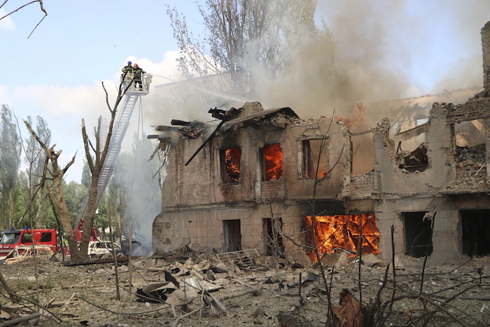 En esta foto distribuida por el Servicio Estatal de Emergencias de Ucrania, los bomberos echan agua sobre un policlínico tras un ataque ruso a la ciudad de Dnipró, Ucrania, viernes 26 de mayo de 2023.