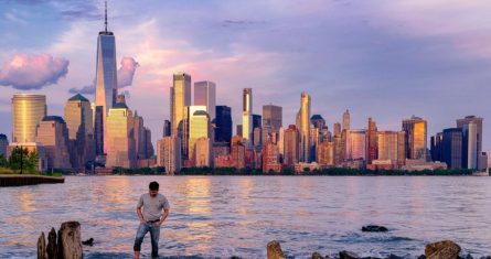 Un hombre comprueba dónde pisa mientras camina por el agua en el Canal Morris en Jersey, Nueva Jersey, mientras se pone el sol con Manhattan de fondo, el 31 de mayo de 2022. Foto: J. David Ake, Archivo, AP