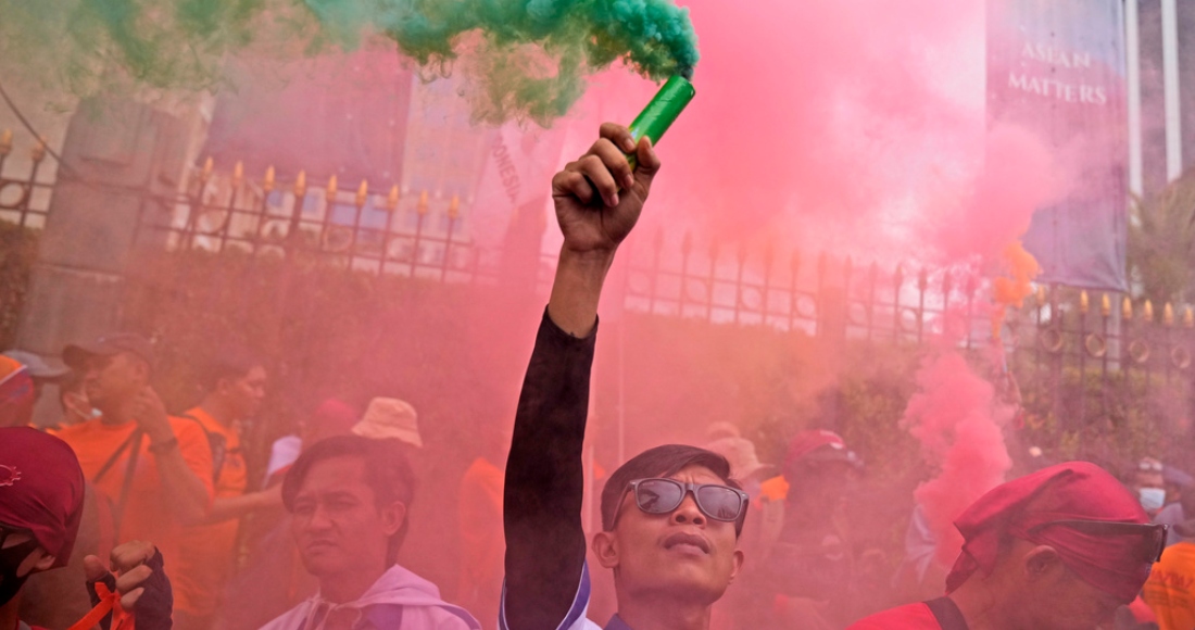 Un trabajador sostiene una bengala durante una manifestación del Primero de Mayo en Yakarta, Indonesia, el lunes 1 de mayo de 2023. Trabajadores y activistas en Asia reclamaban salarios más altos y mejores condiciones de trabajo, entre otras demandas.