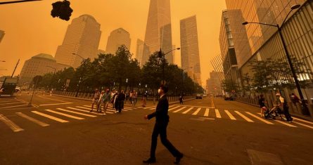 Peatones pasan junto al One World Trade Center (centro), en medio de la humareda causada por los incendios forestales en Canadá, el 7 de junio de 2023, en la Ciudad de Nueva York.