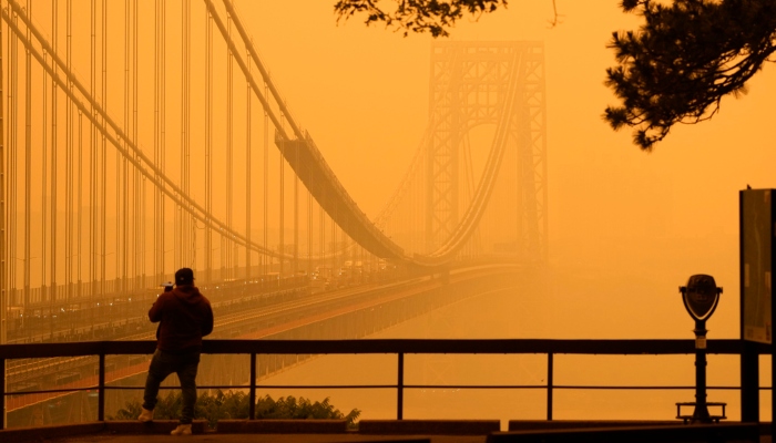 Un hombre conversa por su teléfono en medio de una bruma de humo cerca del puente George Washington, en esta imagen tomada desde Fort lee, Nueva Jersey, el miércoles 7 de junio de 2023. FOTO: Seth Wenig, AP