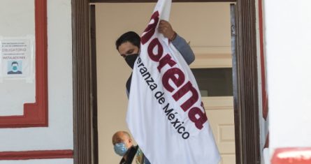 Un hombre acomoda una bandera de Morena durante el anuncio de coalición entre el partido en el poder y Nueva Alianza para el Proceso Electoral 2021.