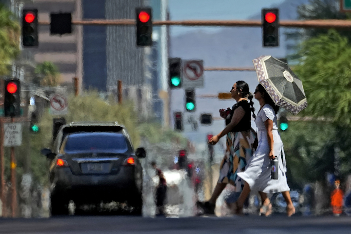 Dos mujeres cruzan una calle el lunes 17 de julio de 2023 en el centro de Phoenix, mientras ondas de calor envuelven a la ciudad.