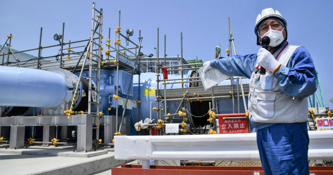 Un empleado del operador de la planta nuclear Fukushima Daiichi, Tokyo Electric Power Company Holdings (Tepco), explica la instalación que se utilizará para liberar al mar el agua radiactiva y tratada el lunes 26 de junio de 2023, en esa planta de Fukushima, en el norte de Japón. Foto: Kyodo News, AP