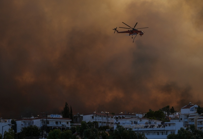 Un helicóptero sobrevuelva un incendio en la localidad de Gennadi, en la isla de Rodas, en el sureste de Grecia, el 25 de julio de 2023. Foto: Petros Giannakouris, AP