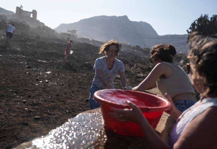 Turistas alemanes y residentes tratan de extinguir un incendio cerca del balneario costero de Lindos, en la isla de Rodas, en el sureste de Grecia, el 24 de julio de 2023. Foto: Petros Giannakouris, AP