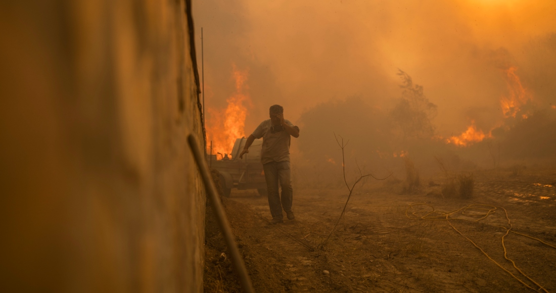 Un residente corre para evitar las llamas de un incendio localizado en Gennadi, en la isla de Rodas, en el sureste de Grecia, el 25 de julio de 2023. Foto: Petros Giannakouris, AP