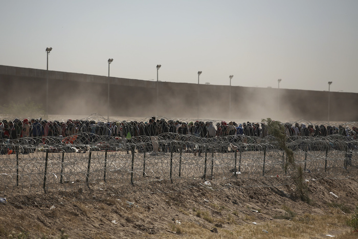 Migrantes alineados entre una valla con alambre de púas y el muro fronterizo entre Estados Unidos y México, visto desde Ciudad Juárez, México, el 9 de mayo de 2023.