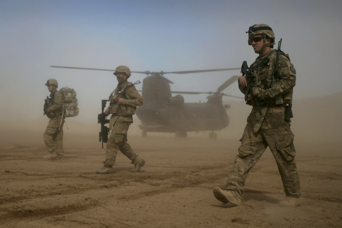 Soldados estadounidenses, que forman parte de la Fuerza Internacional de Asistencia para la Seguridad (ISAF) dirigida por la OTAN, caminan frente a un helicóptero estadounidense Chinook en Shindand, al oeste de Kabul, Afganistán, el 28 de enero de 2012.