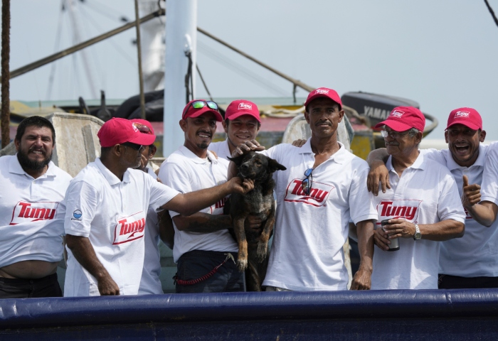 La tripulación del atunero mexicano María Delia posa para las fotos con Bella, la perra del australiano Timothy Lyndsay Shaddock, ambos rescatados de un catamarán dañado en el Océano Pacífico, a su llegada al puerto de Manzanillo, México, el martes 18 de julio de 2023. Foto: Fernando Llano, AP