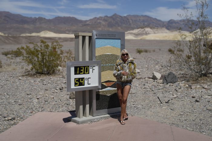 Una mujer posa junto a un termómetro, el domingo 16 de julio de 2023, en el Parque Nacional del Valle de la Muerte, en California.