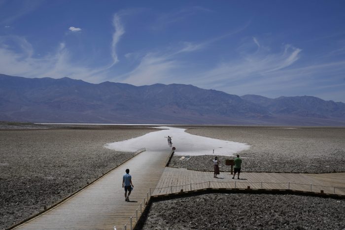 Varias personas caminan por una plataforma de madera en Badwater Basin, el domingo 16 de julio de 2023, en el Parque Nacional del Valle de la Muerte, en California.