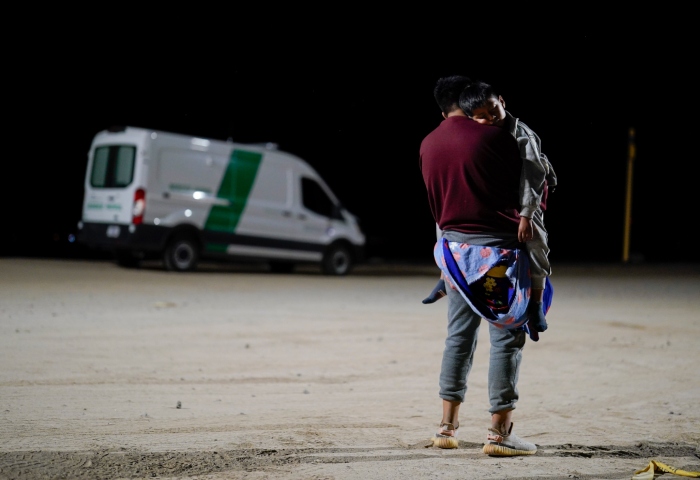 Un hombre colombiano carga a su hijo mientras espera a solicitar asilo después de cruzar la frontera desde México, el martes 11 de julio de 2023, cerca de Yuma, Arizona. Foto: Gregory Bull, AP