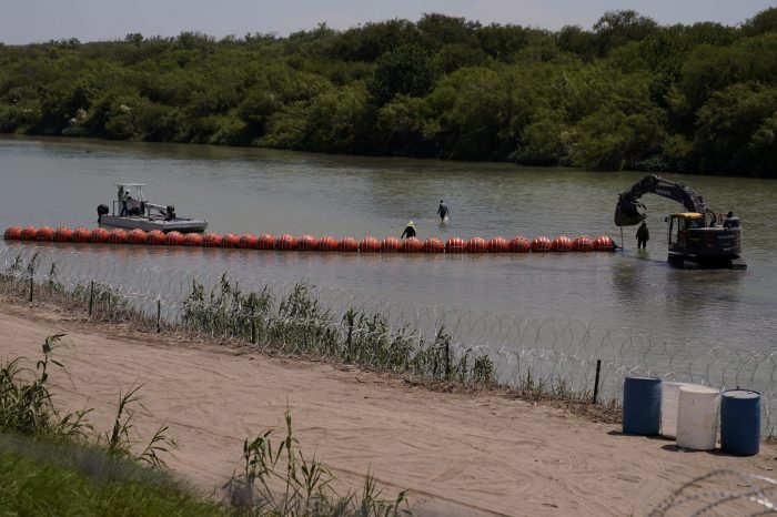 Trabajadores extienden una línea de grandes boyas a modo de barrera flotante en medio del río Bravo, cerca de Eagle Pass, Texas, el martes 11 de julio de 2023.