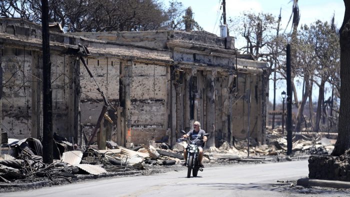 Un hombre circula en motocicleta entre los daños causados por un incendio, el 11 de agosto de 2023, en Lahaina, Hawai. 