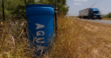 Una estación de agua para migrantes que contiene dentro bidones sellados de agua está ubicada al lado de una cerca próxima a una carretera en el condado rural Jim Hogg, en Texas, el martes 23 de julio de 2023.