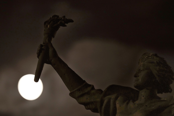 Una súperluna se alza en el cielo por detrás de una estatua de Marte, en el centro de Beirut, Líbano, el 30 de agosto de 2023.