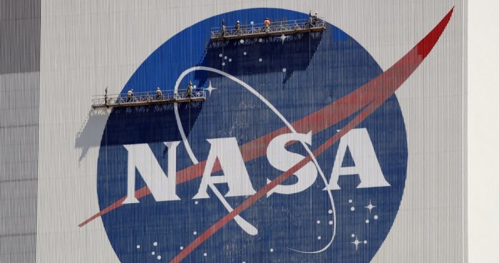 Trabajadores en andamios repintan el logo de la NASA en el Centro Espacial Kennedy, Cabo Cañaveral, Florida, 20 de mayo de 2020.