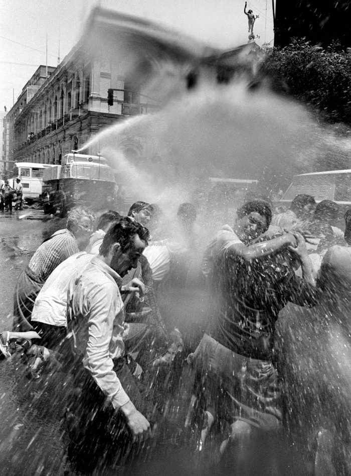 La policía arroja una mezcla de agua y gases lacrimógenos a miembros del Movimiento Contra la Tortura de Sebastián Acevedo, en el exterior del diario El Mercurio, en el centro de Santiago, Chile, el 24 de noviembre de 1983. 