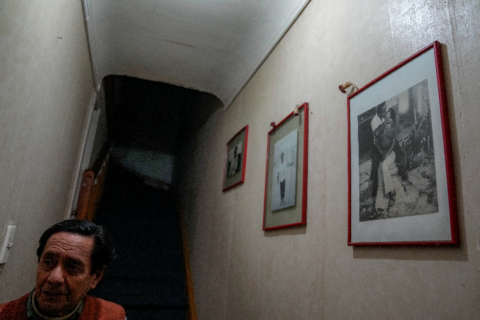 Lautaro Videla camina dentro de su casa junto a una foto de su hermana Lumi Videla besando a su esposo Sergio Pérez, en Santiago, Chile, el miércoles 2 de agosto de 2023.