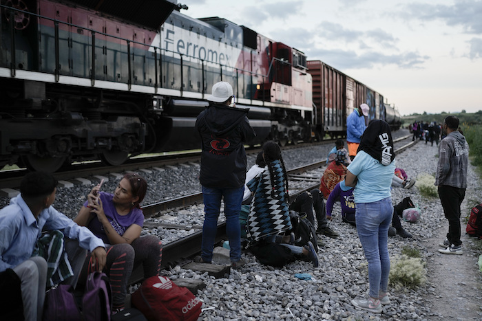 Migrantes observan un tren en marcha junto a las vías en las que esperan para subir a bordo de un vagón para dirigirse al norte del país, en Huehuetoca, México, el 19 de septiembre de 2023.