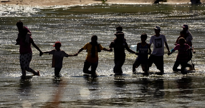 Migrantes forman una cadena humana para cruzar el Río Bravo desde México a Estados Unidos, el 21 de septiembre de 2023, en Eagle Pass, Texas.