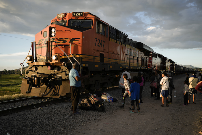 Migrantes ven pasar un tren mientras esperan a lo largo de las vías con la esperanza de subir a un tren de carga que vaya hacia el norte, uno que se detenga el tiempo suficiente para que puedan subirse, el 19 de septiembre de 2023, en Huehuetoca, México.