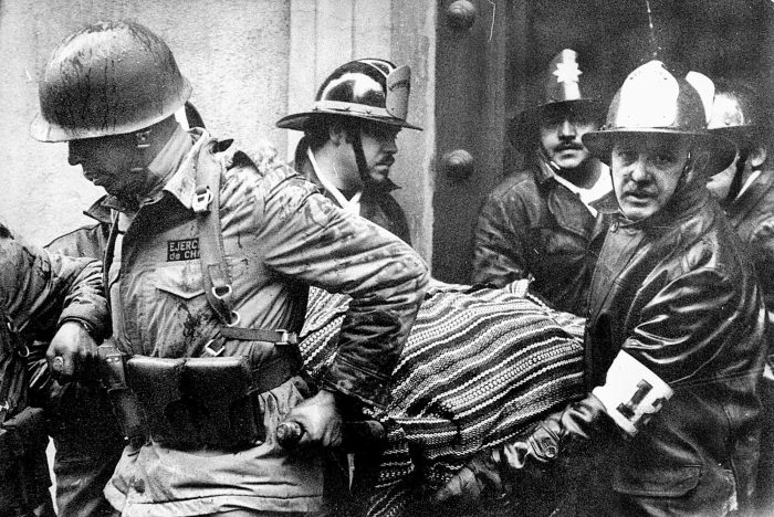 En esta imagen de archivo, soldados y bomberos sacan el cuerpo del Presidente chileno Salvador Allende, envuelto en un poncho boliviano, del palacio presidencial de La Moneda tras un bombardeo durante el golpe de Estado liderado por el general Augusto Pinochet, en Santiago, Chile, el 11 de septiembre de 1973.