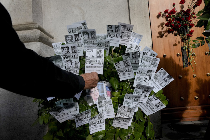 Una persona coloca una tarjeta de recuerdo en la puerta lateral este del palacio presidencial de La Moneda, a través de la cual el cuerpo del Presidente Salvador Allende fue transportado por soldados y bomberos hace 50 años después del golpe militar que derrocó a su Gobierno en Santiago, Chile, el lunes 11 de septiembre de 2023.