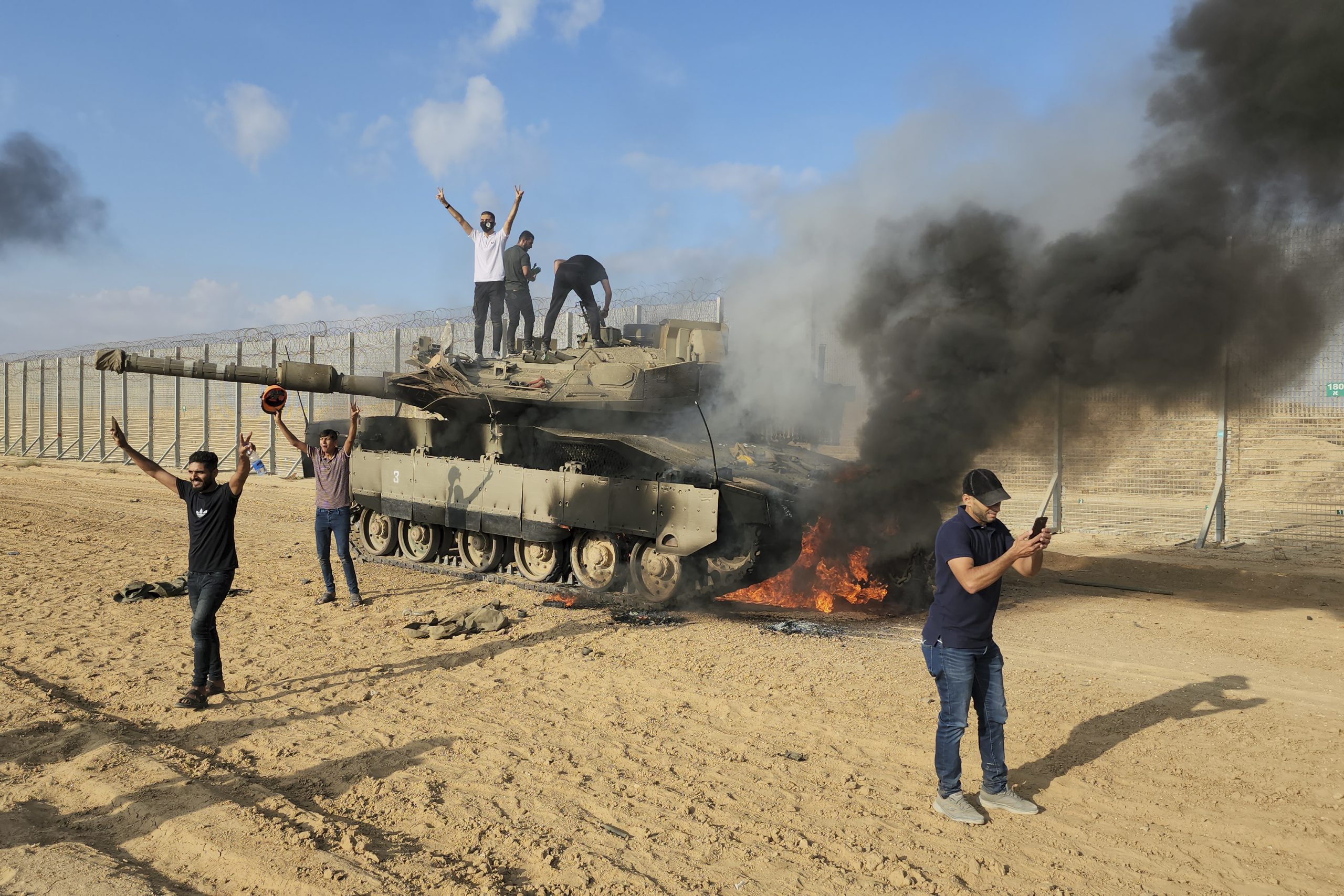 Palestinos festejan al lado de un tanque israelí destruido en una valla en la Franja de Gaza, al este de Khan Younis, el sábado 7 de octubre de 2023. Foto: Hassan Eslaiah, AP