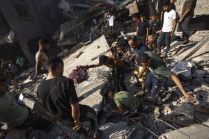 Palestinos buscan cadáveres y sobrevivientes entre los restos de un edificio residencial arrasado tras un ataque aéreo israelí sobre el campo de refugiados de Al Shati, el 12 de octubre de 2023. Foto: Fatima Shbair, AP