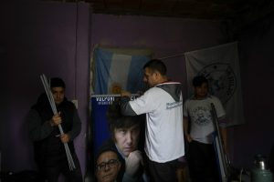 Andrés Ferreira, simpatizante del aspirante presidencial Javier Milei, enrolla unos carteles de campaña del candidato, en su casa del barrio de Fiorito en Buenos Aires, Argentina, el sábado 23 de septiembre de 2023. Ferreira, que trabaja como repartidor en una plataforma digital, también hace promoción por Milei en la municipalidad de Lomas de Zamora de Buenos Aires. Foto: Natacha Pisarenko, AP