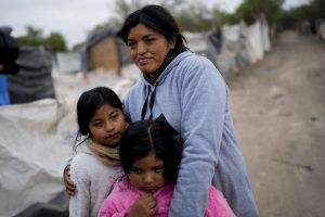 Paola Aguirre abraza a sus hijas Keila, a la derecha, y Loana fuera de su casa en Salta, Argentina, el miércoles 4 de octubre de 2023. Aguirre, que vive en una casita levantada con maderas cerca de un vertedero, tiene puesta su esperanza en el candidato presidencial Javier Milei, un economista y legislador instigador que se describe a sí mismo como un anarco-capitalista y que dice que la respuesta a la creciente inflación anual que ahora ronda el 140 por ciento pasa por eliminar el Banco Central y dolarizar la economía. Foto: Natacha Pisarenko, Ap