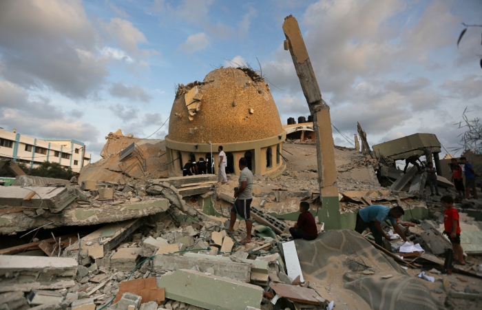 Gente ante una mezquita destruida por un ataque aéreo israelí en Khan Younis, Franja de Gaza, el domingo 8 de octubre de 2023.