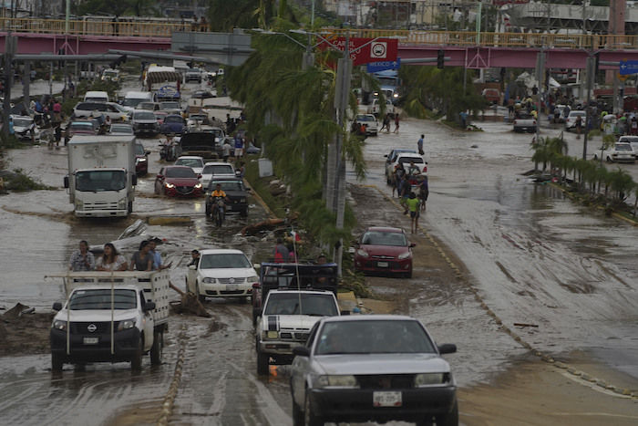 Autos cruzan una avenida anegada tras el paso del huracán "Otis" por Acapulco, México, el 25 de octubre de 2023.