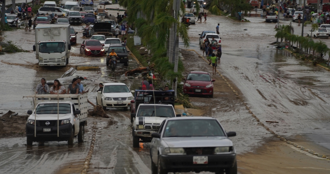 Autos cruzan una avenida anegada tras el paso del huracán "Otis" por Acapulco, México, el 25 de octubre de 2023.