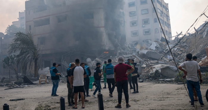 En esta imagen de archivo, reporteros observan mientras palestinos inspeccionan un edificio alcanzado por un bombardeo israelí en la Ciudad de Gaza, 8 de octubre de 2023.