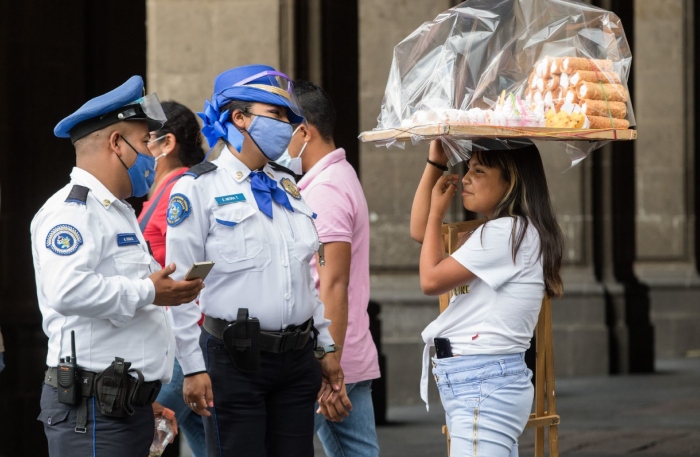 Policías capitalinos impiden a una joven vender su mercancía en el zócalo.